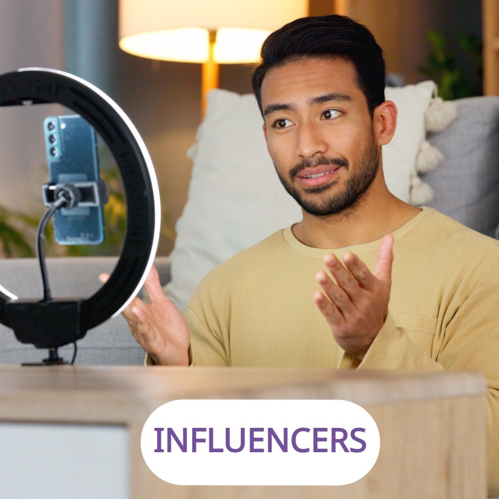 A man recording a livestream at home with a phone and ring light